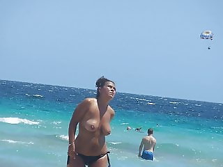 A topless busty girl comes out of the sea